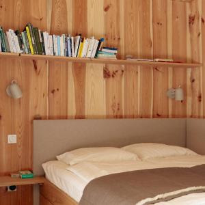 a bedroom with a bed and a shelf with books at baumhaus buchengrün in Dobl-Zwaring