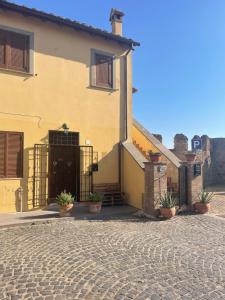 a yellow building with a gate and potted plants at “La Casetta nel Borgo” in Cerveteri
