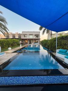 uma piscina com um guarda-sol azul e um edifício em Villa Marina 6 First Row on The Lake em El Alamein