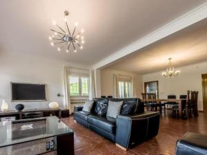 a living room with a black leather couch and a television at Villa con piscina, jardín y aire acondicionado en La Eliana-L'Eliana in Valencia