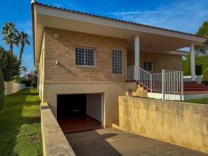 una casa di mattoni con un garage di fronte di Villa con piscina, jardín y aire acondicionado en La Eliana-L'Eliana a Valencia