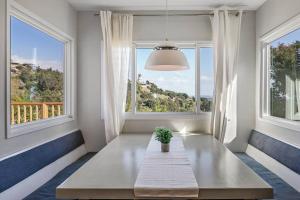 a dining room with a table and two windows at Breathtaking Hollywood Hills Vacation Home in Los Angeles
