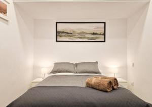 a bed in a white bedroom with a picture on the wall at Apartamento Altimiras 'Las Ventas' in Madrid