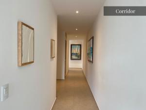 a hallway with white walls and paintings on the walls at Beautiful Aria Ocean 401 QueridaEstancia in Nuevo Vallarta