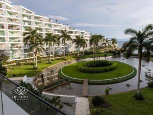 um grande edifício de apartamentos com palmeiras e um parque em Beautiful Aria Ocean 401 QueridaEstancia em Nuevo Vallarta 