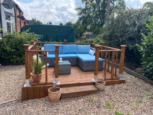 a wooden patio with a blue couch on a deck at Santalijshoteliers Rm5 in Leicester