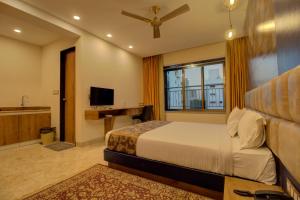 a bedroom with a bed and a desk and a television at Greenstones Boutique Hotel in Nashik
