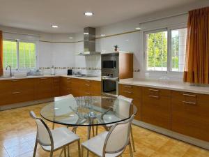 a kitchen with a glass table and white chairs at Villa con piscina, jardín y aire acondicionado en La Eliana-L'Eliana in Valencia