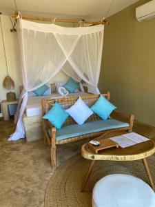a bedroom with a bed with blue pillows and a table at Zen Boutique Resort in Jambiani