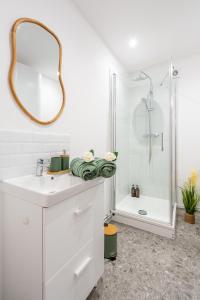 a white bathroom with a sink and a shower at L'écrin des Bois - Proche aéroport Beauvais, Chantilly, forêt de Hez-Froidmont, parking public gratuit, Wifi & Netflix in Clermont