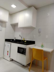uma cozinha com armários brancos, uma mesa e uma cadeira amarela em Compact Tambaú 408 em João Pessoa