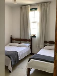 2 camas en una habitación con ventana en Pouso dos Viajantes Unidade Centro OuroPreto, en Ouro Preto