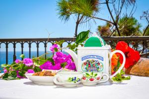 a table with two cups and a tea pot and flowers at Casa di Mare Barabba in Santa Teresa di Riva