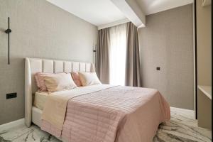 Un dormitorio con una cama con una manta rosa y una ventana. en Apt "Royal Oak" 2 Bedroom with Garage Parking, en Budva