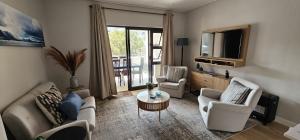 a living room with a couch and chairs and a television at 116 The Esplanade in Hermanus