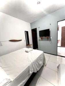 a white bedroom with a bed and a flat screen tv at Pousada Apart Amor de Jeri in Jericoacoara