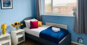ケンブリッジにある3 Bedroom House Garden Free Parking 15 min to centre 5 min to motorwayの青い小さなベッドルーム(カラフルな枕付きのベッド1台付)