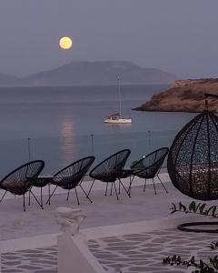 un grupo de sillas sentadas en la playa por la noche en Anatoli Studios, en Schinoussa