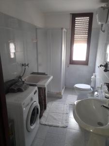 baño blanco con lavadora y lavamanos en Casa vacanza bel vedere, en Villamassargia