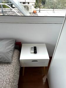 a bed and a white table with a remote control on it at Glyfada One-Bedroom Studio in Athens