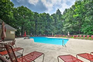 a swimming pool with red chairs and a group of trees at Wintergreen Resort Condo with Deck, 0 3 Mi to Slopes in Lyndhurst