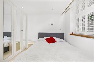 a white bedroom with a red pillow on a bed at LONDON ONE BED ANNEX in London