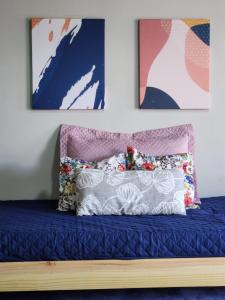 1 cama con sábanas azules y 2 cuadros en la pared en Apart Samambaia en Puerto Iguazú