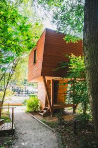 Una pequeña casa de madera con un porche en el lateral. en Utopia Village - Art & Nature Lodges en Jurbise