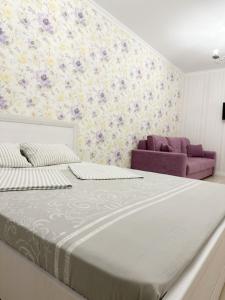 Un dormitorio con una cama grande y un sofá púrpura. en Апартаменты в ЖК Аманат, en Almaty