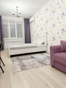 1 dormitorio con cama y sofá púrpura en Апартаменты в ЖК Аманат, en Almaty