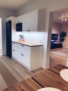 uma cozinha com armários brancos e um frigorífico preto em Moderni huoneisto Salon keskustassa em Salo