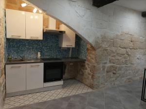 a kitchen with white cabinets and a stone wall at Grande maison traversante. in Saint-Gilles