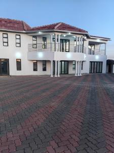 a large white building with a brick driveway at Ngqamakwe Luxury Guest House and Conference Centre in Nqamakwe