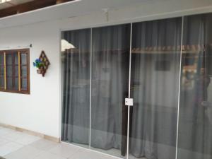 - une porte coulissante en verre dans une chambre dotée de rideaux gris dans l'établissement Kitnet Praia de Ubatuba, à São Francisco do Sul