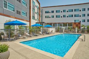 a swimming pool with chairs and umbrellas and a building at Element Albuquerque Uptown in Albuquerque
