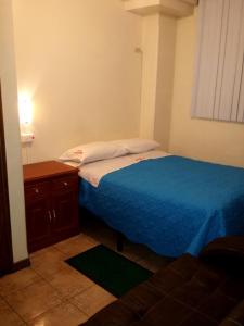 a small bedroom with a blue bed and a dresser at Hostal David Alejandro in Quito