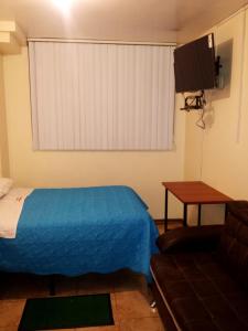 a room with a bed and a television and a couch at Hostal David Alejandro in Quito