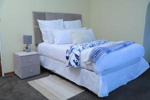 uma cama com lençóis azuis e brancos e uma mesa de cabeceira em 540 BIRSTON em Pretoria