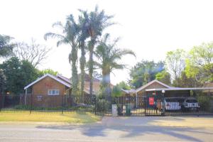 a house with a fence and a palm tree at 540 BIRSTON in Pretoria