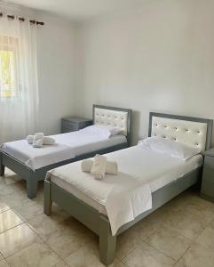 two beds in a room with white walls at Marl's Home in Berat