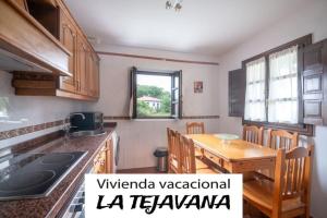 a kitchen with a wooden table and a dining room at vivienda vacacional la tejavana in Llames de Pría