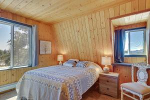 a bedroom with a bed and a chair and two windows at Lake George Cabin with Deck and Mountain Views! in Florissant +37 photos