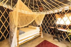 a bedroom with a canopy bed in a room with a desk at Corumbau Cura in Prado