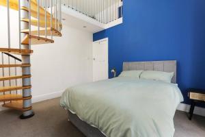 1 dormitorio con paredes azules y 1 cama con escalera. en Semi-Detached House Featuring a Mezzanine Level en Nether Edge