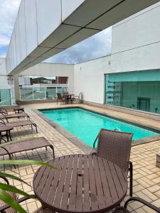 ヴィトーリアにあるPraia do Canto Apart Hotel quarto sala e varanda andar altoのスイミングプール(椅子、テーブル付)