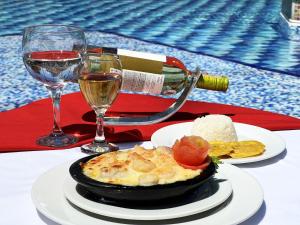 een tafel met een bord eten en twee glazen wijn bij Tequendama Hotel Campestre Villavicencio in Villavicencio