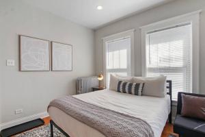 1 dormitorio con 1 cama, 1 silla y 2 ventanas en Comfy and Serene Studio Apt in Chicago - Pensacola 2W, en Chicago