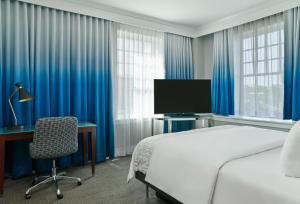 1 dormitorio con 1 cama, escritorio y TV en Le Meridien Dallas, The Stoneleigh en Dallas