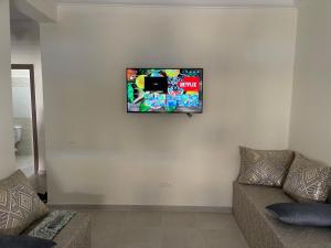 TV de pantalla plana colgada en la pared de la sala de estar. en Jardin hay chrifia, en Marrakech