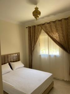 sypialnia z łóżkiem i oknem z żyrandolem w obiekcie Jardin hay chrifia w Marakeszu